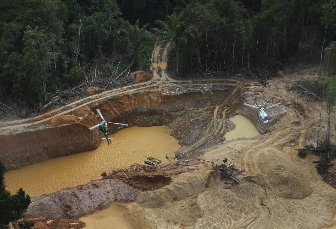 FILE - A Brazil Environmental Agency helicopter flies over an illegal mining camp during an operation to try to contain illegal mining in Yanomami Indigenous territory, Roraima state, Brazil, Feb. 11, 2023. Rio de Janeiro’s Salgueiro samba school, that paid tribute to the Yanomami Indigenous group in the Carnival parade at the Sambrodome on Sunday, Feb. 11, 2024, is seeking to draw attention to the devastating effects brought by illegal mining inside Yanomami territory, including widespread river contamination, famine and disease. (AP Photo/Edmar Barros, File)