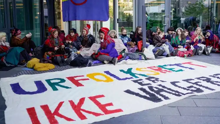 Activists wearing traditional Sami outfits sit in protest outside the entrance of Statkraft, a state-owned company that operates 80 of the wind turbines at Fosen. - Copyright Cornelius Poppe/NTB Scanpix via AP, File