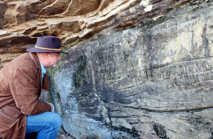 David Sibray examines the Lynco Petroglyph, also known as the Luther Elkins Petroglyph, near Oceana, West Virginia.