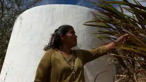 Agustina Ortiz, 45, stands beside her 20,000-liter ferrocement tank at her home in the community of Xixovo, Oaxaca, on 5 December 2023 (Credit: Stephania Corpi Arnaud)