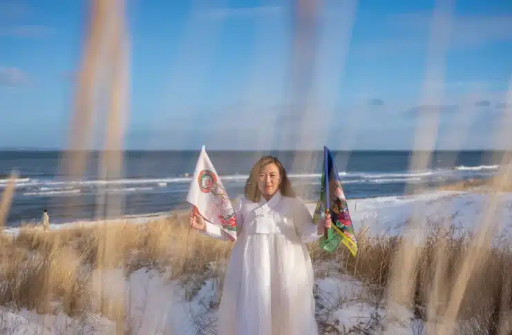 Helena Soholm holds up the five directional flags of Korean shamanism in Dronningmølle, Denmark.