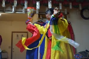 Photo of a woman wearing a colorful outfit jumping during a ceremonial ritual.Long Island-based shaman Jennifer Kim in a ceremonial ritual.

Courtesy of Jennifer Kim