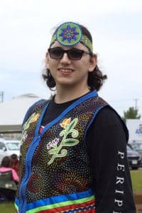 Hoop dancer River Christie-White at 2024 Two-Spirit Powwow in Toronto. Christie-White wears regalia with red, yellow and green to honour their experience living with Asperger’s syndrome, and founded Hoops for Hope, an organization that fosters inclusion and support for Indigenous children with special needs.