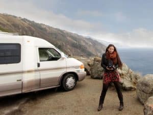 A self portrait of Matika Wilbur. A woman stands next to a van on the edge of a cliff.Matika Wilbur.Matika Wilbur