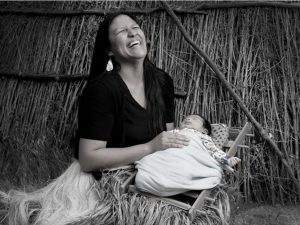A Native American woman laughs while holding her baby.Myra Masiel Zamora, Pechanga Band of Luiseno Indians.Matika Wilbur