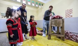 Children dressed in traditional outfits watch as men prepare portions of meat as part of Algeria's Tamechrit, based on the Amazigh New Year's traditions, in Bajaia, on January 11, 2025. (AFP)